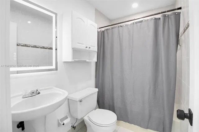 a bathroom with a sink a toilet and shower curtain