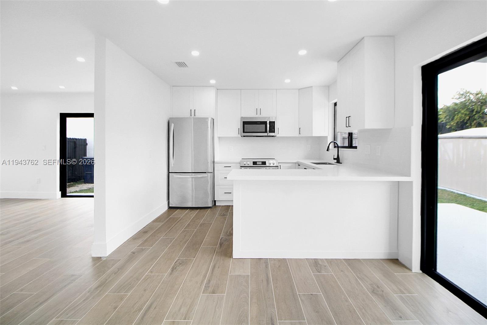 13379 Northwest 3rd Terrace Miami, FL 33182 - Photo 6 of 23 a kitchen with stainless steel appliances granite countertop a refrigerator a sink a stove and white cabinets with wooden floor