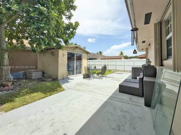 a view of a backyard with couches potted plants and large tree
