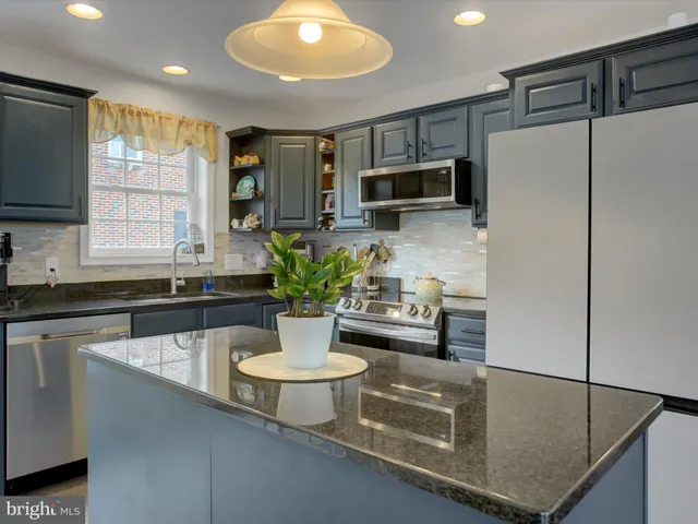 a kitchen with stainless steel appliances granite countertop a sink a stove a microwave a refrigerator a counter space and cabinets