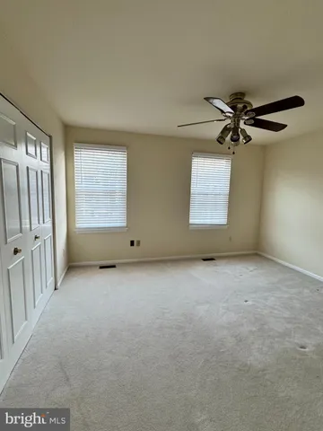 an empty room with a ceiling fan and window