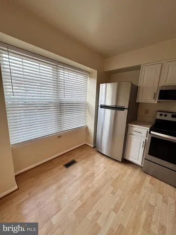 a view of kitchen with stainless steel appliances wooden floor and window