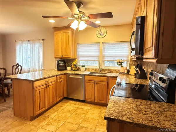 a kitchen with stainless steel appliances granite countertop a sink a stove counter space and a window
