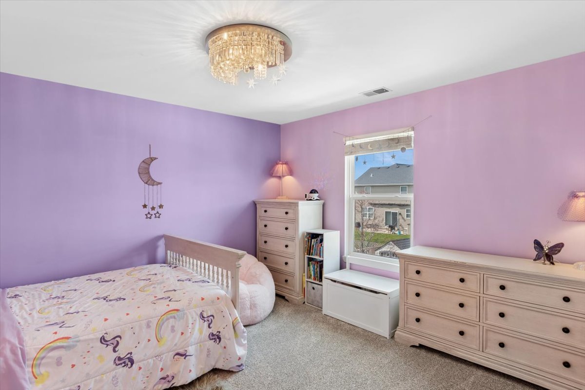 724 North Misty Ridge Drive Romeoville, IL 60446 - Photo 14 of 26 a bedroom with a bed and a chandelier