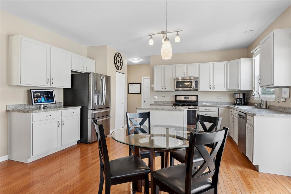 724 North Misty Ridge Drive Romeoville, IL 60446 - Photo 7 of 26 a kitchen with stainless steel appliances a refrigerator a stove a dining table and chairs