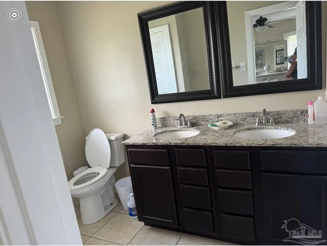 a bathroom with a granite countertop toilet sink and mirror