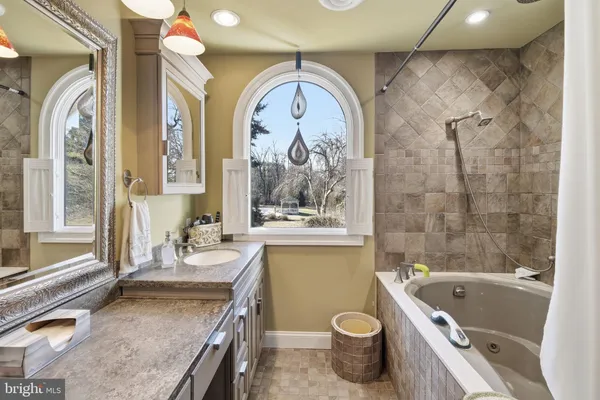 a bathroom with a granite countertop sink a large mirror a bathtub and a toilet