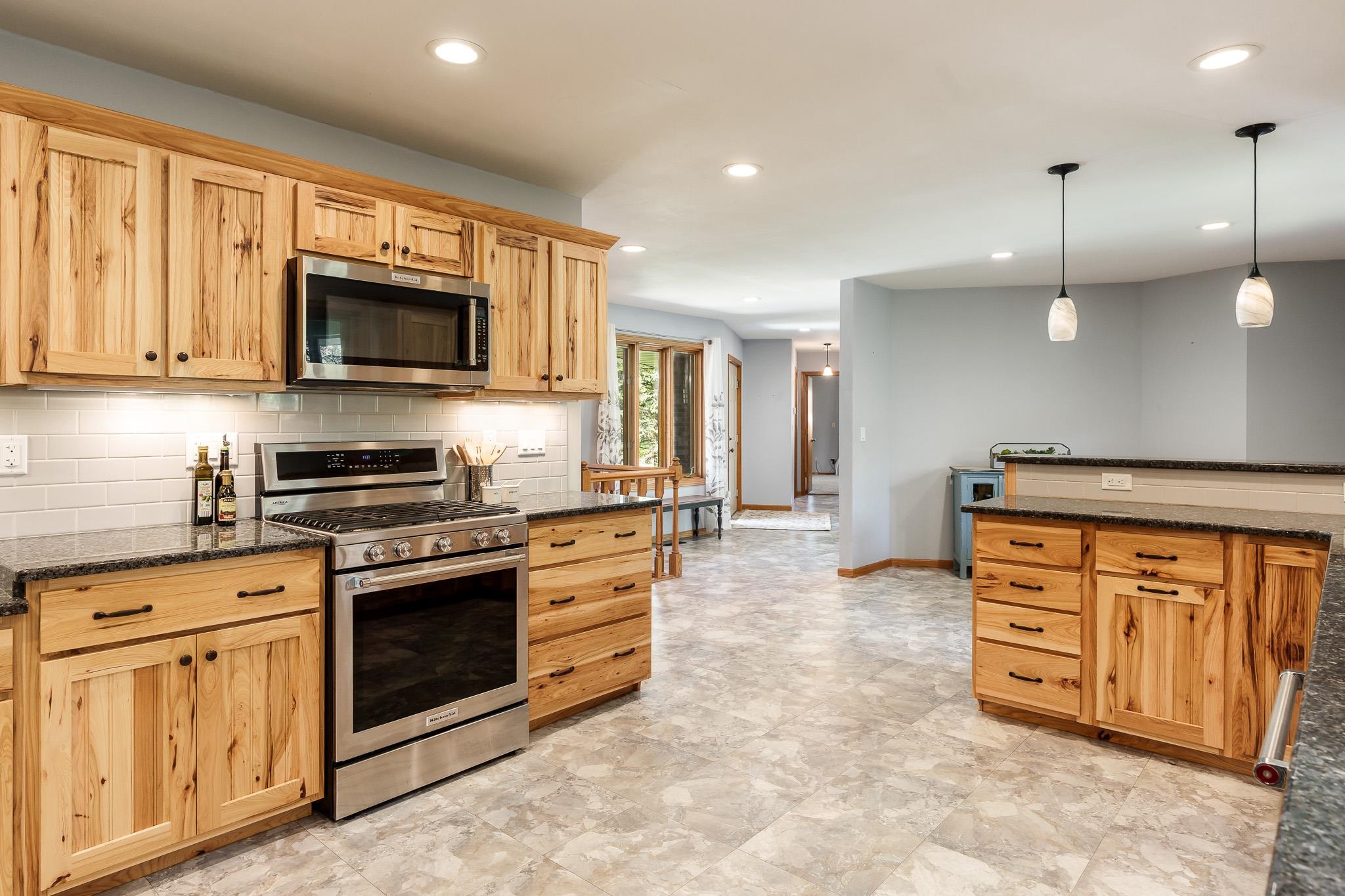 10249 Atwood Road Roscoe, IL 61073 - Photo 21 of 58 a kitchen with stainless steel appliances granite countertop a stove top oven a sink dishwasher a dining table and chairs with wooden cabinets