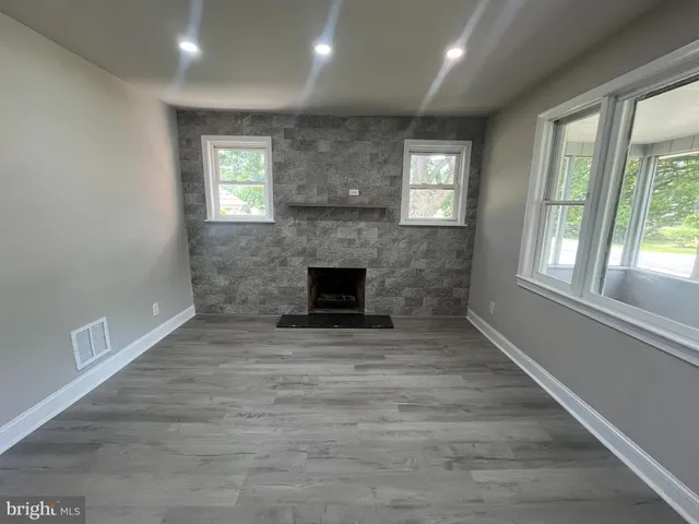 an empty room with windows and fireplace