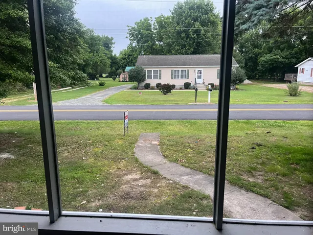 a view of a yard in front of a house with large trees