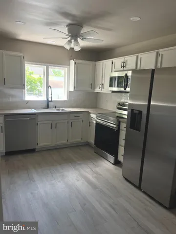 a large kitchen with stainless steel appliances granite countertop a stove a sink and a refrigerator