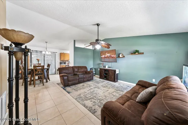 a living room with furniture a dining table and a chandelier
