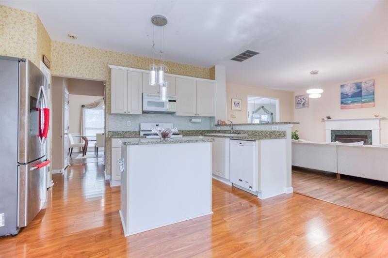1008 Post Horn Run Lawrenceville, GA 30045 - Photo 12 of 64 a kitchen with stainless steel appliances kitchen island granite countertop a stove a sink a refrigerator and white cabinets with wooden floor