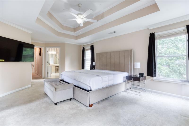 1008 Post Horn Run Lawrenceville, GA 30045 - Photo 50 of 64 a spacious bedroom with a large bed a flat screen tv and a large window