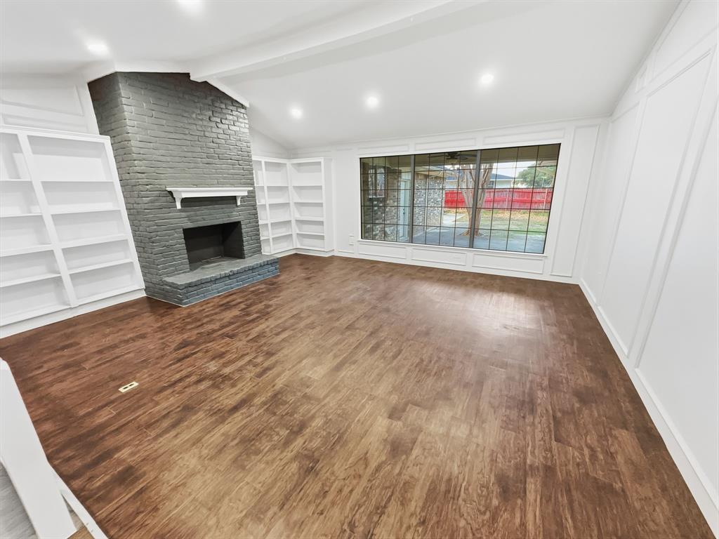 2409 Castle Street Irving, TX 75038 - Photo 4 of 32 an empty room with wooden floor fireplace and windows