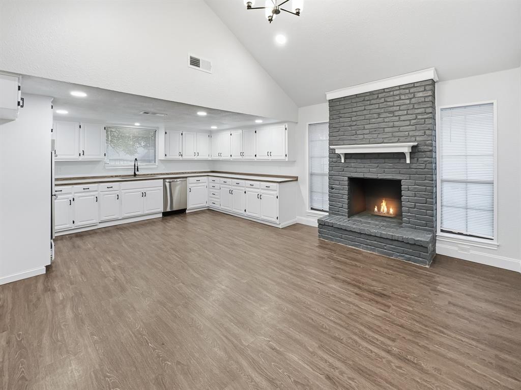 2409 Castle Street Irving, TX 75038 - Photo 6 of 32 a large white kitchen with cabinets a fireplace and a wooden floor