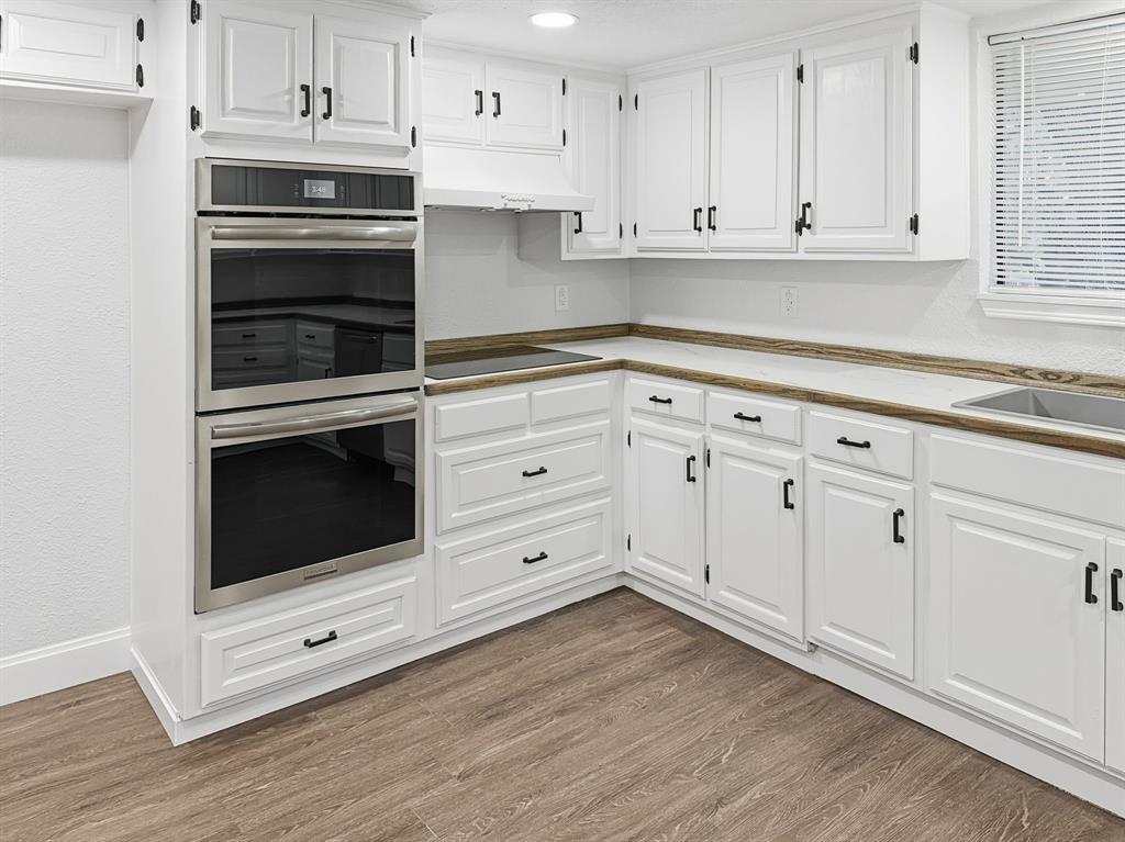 2409 Castle Street Irving, TX 75038 - Photo 7 of 32 a kitchen with white cabinets and appliances