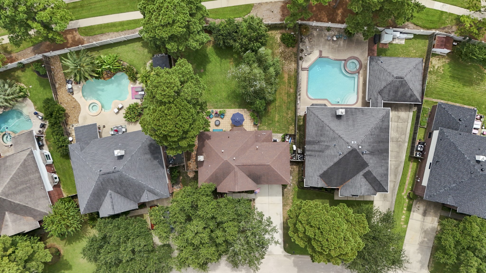 20235 Eden Pines Spring, TX 77379 - Photo 38 of 50 From above, the backyard layout becomes much clearer. Cross fencing divides the yard into two distinct outdoor areas, creating a separate dog run along the right side of the property while leaving a substantial main yard open behind the large paver patio. The smaller concrete grilling area and fenced service/storage space sit close to the house, while mature trees add shade throughout. This view also shows just how much usable yard remains beyond the patio, with no rear neighbors directly behind.