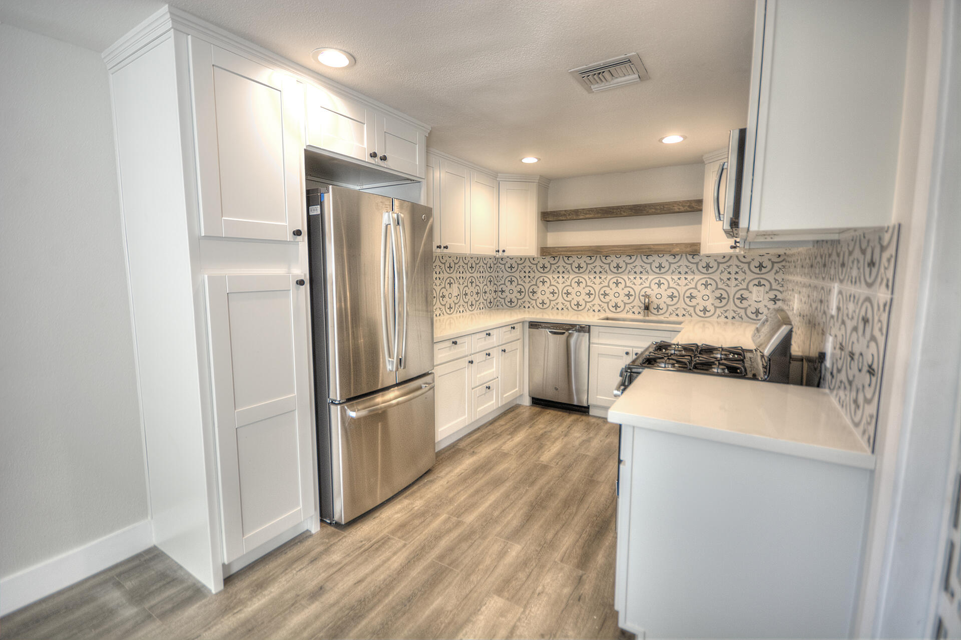 a kitchen with stainless steel appliances granite countertop a refrigerator a stove and a sink
