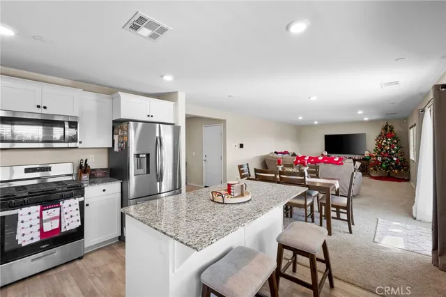 a kitchen with granite countertop a refrigerator stove top oven dining table and chairs