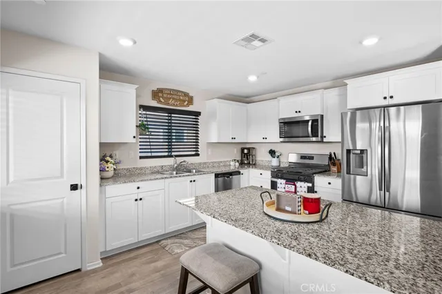 a kitchen with a sink dishwasher a stove a refrigerator cabinets and a dining table with wooden floor