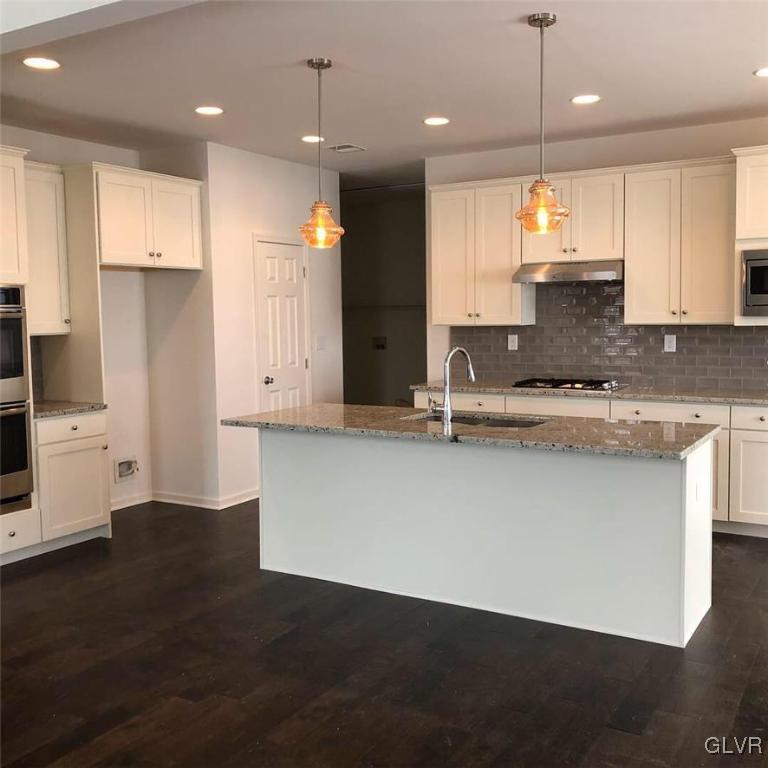 6559 Gun Club Road, Unit 35 Coopersburg, PA 18036 - Photo 20 of 48 a large kitchen with kitchen island white cabinets and stainless steel appliances