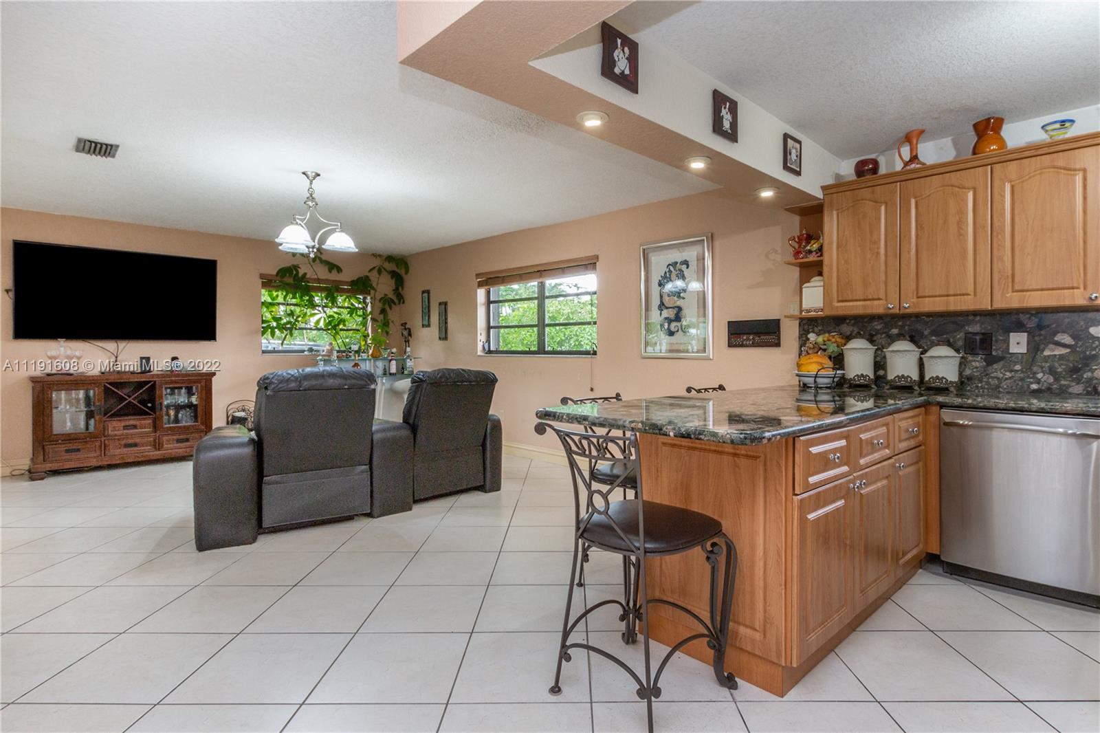 13560 Southwest 2nd Street Miami, FL 33184 - Photo 12 of 50 a kitchen with granite countertop a stove a sink a dining table and chairs