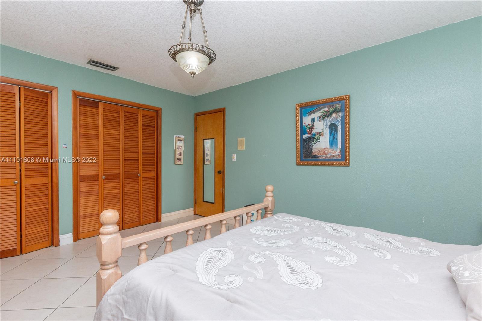 13560 Southwest 2nd Street Miami, FL 33184 - Photo 29 of 50 a bedroom with a large bed and a chandelier