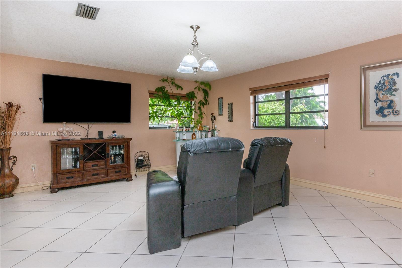 13560 Southwest 2nd Street Miami, FL 33184 - Photo 10 of 50 a living room with furniture a flat screen tv and a chandelier