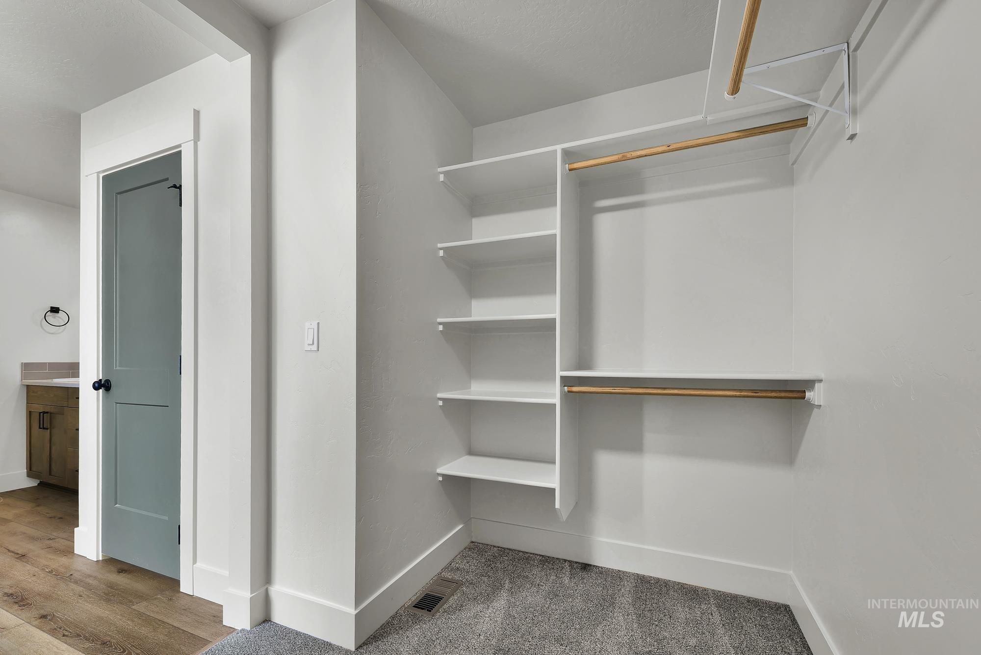 1130 Velvet Loop Wilder, ID 83676 - Photo 25 of 35 Walk-in closet featuring white built-in shelving, multiple hanging rods, and gray carpet flooring