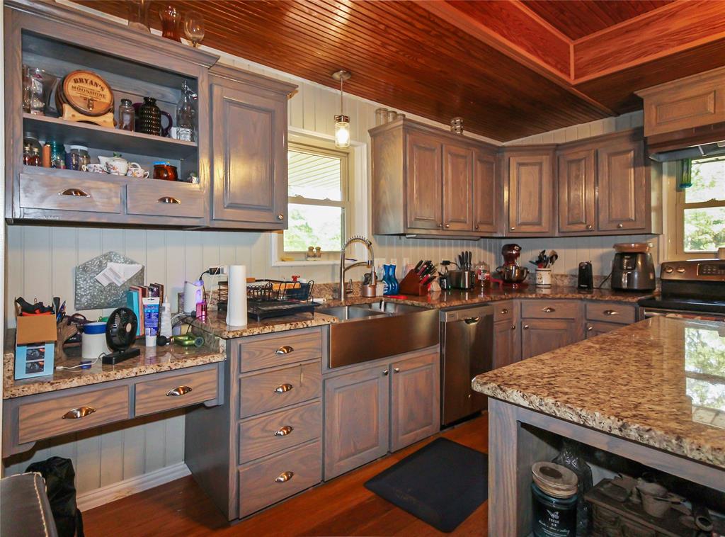 1001 Sandy Ridge Road Scurry, TX 75158 - Photo 17 of 35 Kitchen featuring warm wood-finish plank ceiling, perimeter cabinetry with open shelving, granite countertops, and a stainless steel farmhouse sink