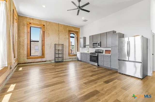 a kitchen with stainless steel appliances a refrigerator and wooden floor