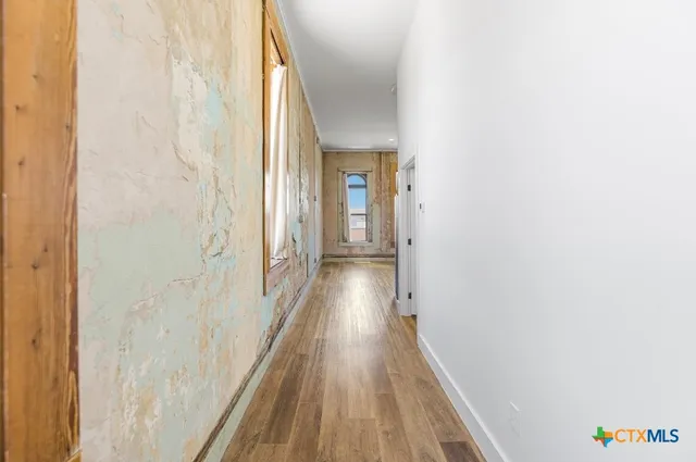 a view of an empty room with wooden floor and windows