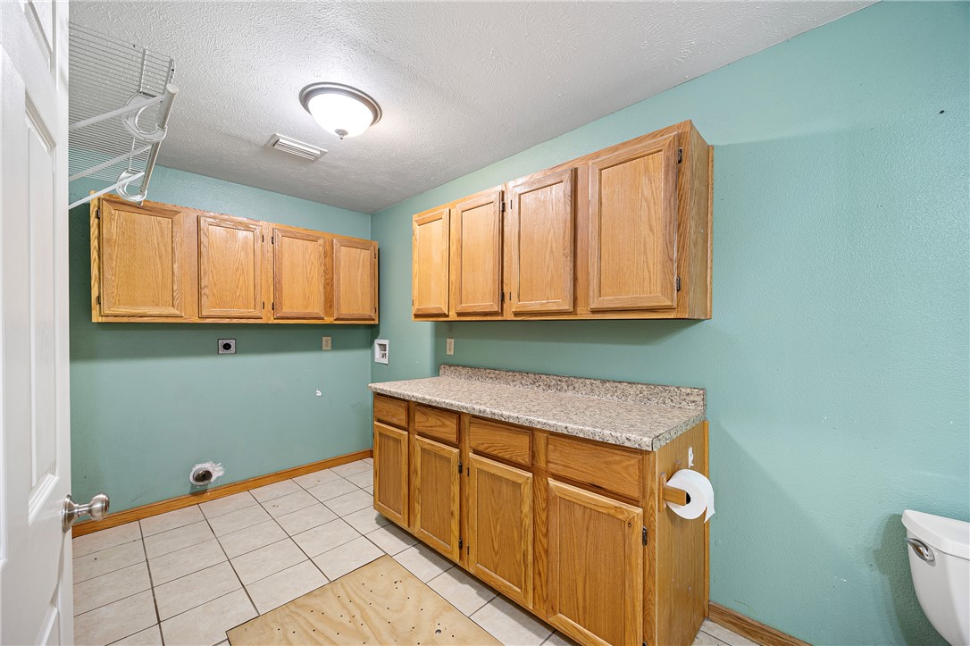 655 Charton Road Morrilton, AR 72110 - Photo 18 of 49 Utility room featuring extensive wood cabinetry, a laminate countertop, and tile flooring