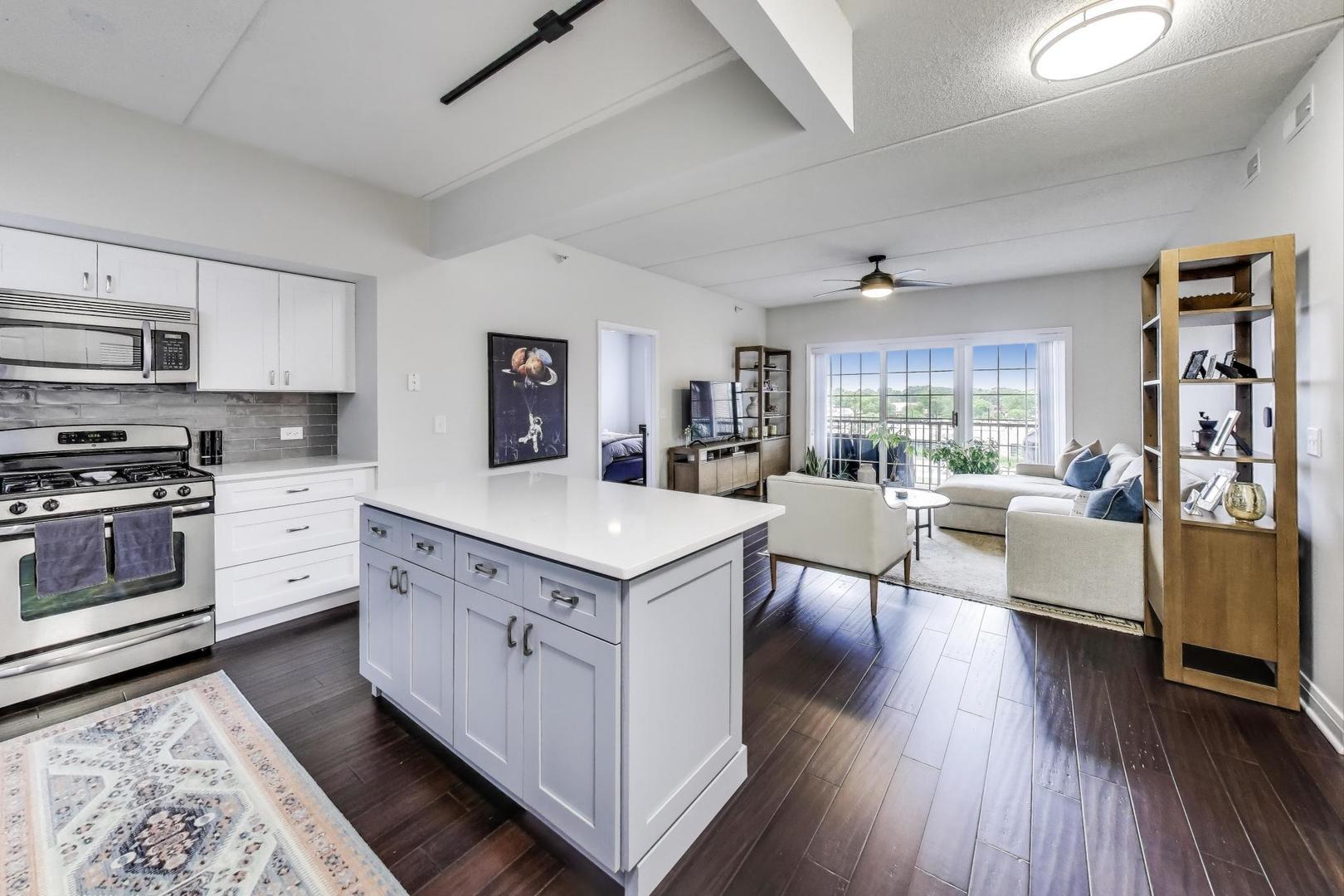 100 South Emerson Street, Unit 415 Mount Prospect, IL 60056 - Photo 2 of 15 a kitchen with stainless steel appliances granite countertop a stove top oven a refrigerator a dining table and chairs with wooden floor