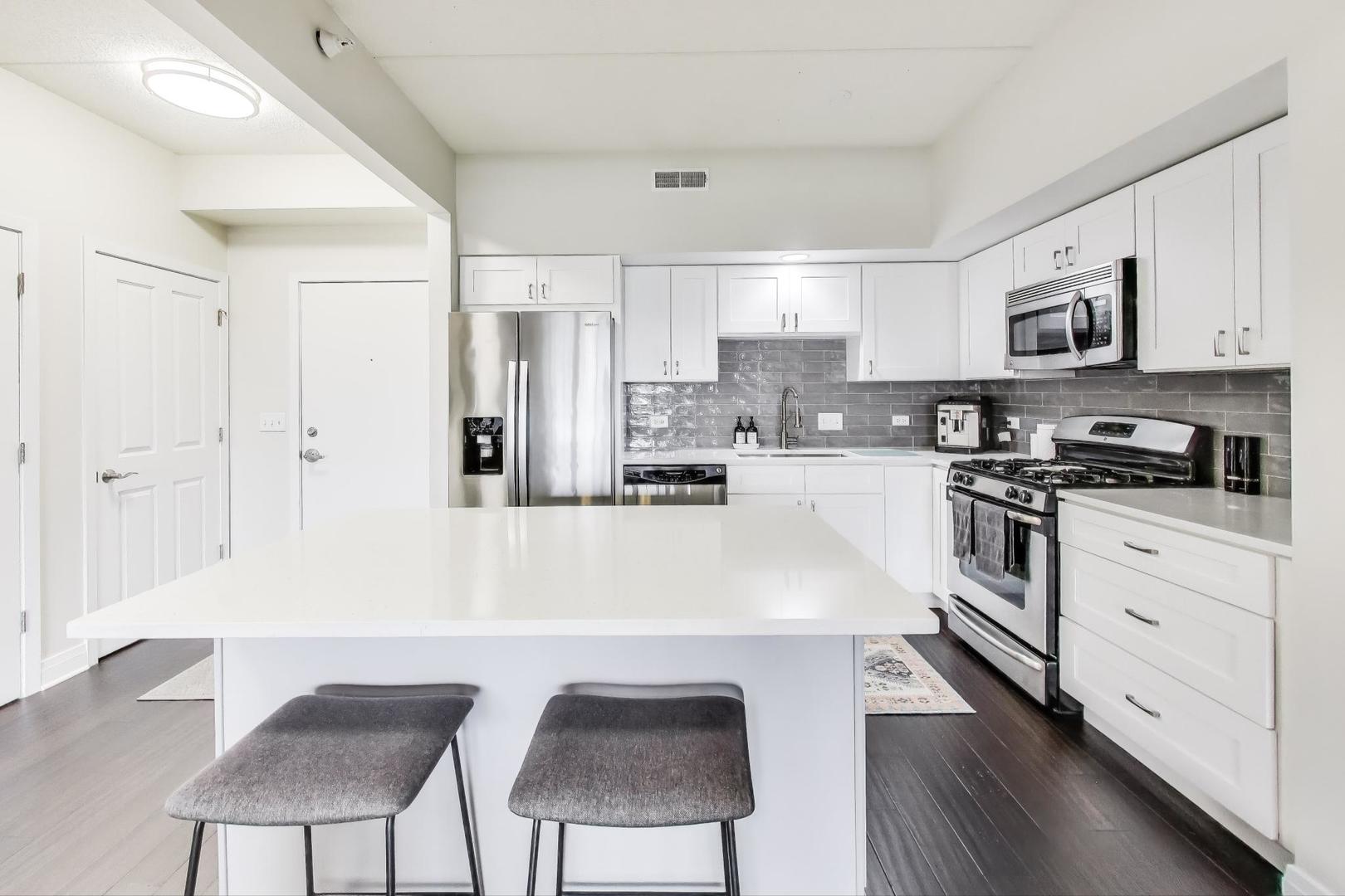 100 South Emerson Street, Unit 415 Mount Prospect, IL 60056 - Photo 6 of 15 a kitchen with stainless steel appliances a white table and chairs in it