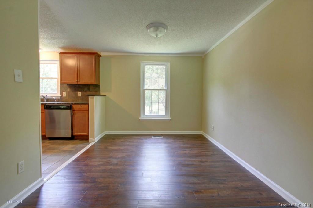 6625 Reddman Road Charlotte, NC 28212 - Photo 4 of 24 an empty room with wooden floor kitchen view and a window