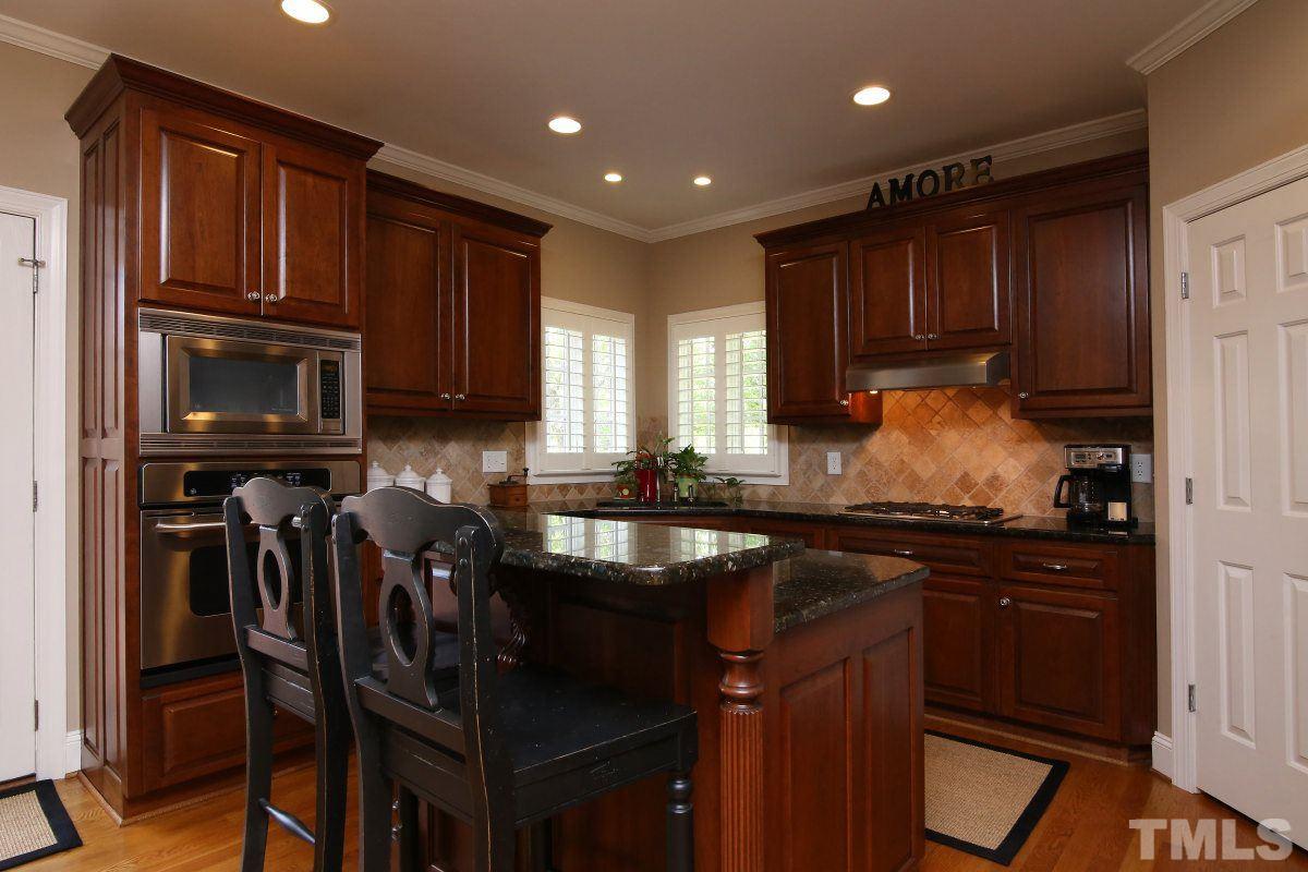 502 Shelley Road Raleigh, NC 27609 - Photo 9 of 25 a kitchen with kitchen island granite countertop wooden cabinets and a stove top oven
