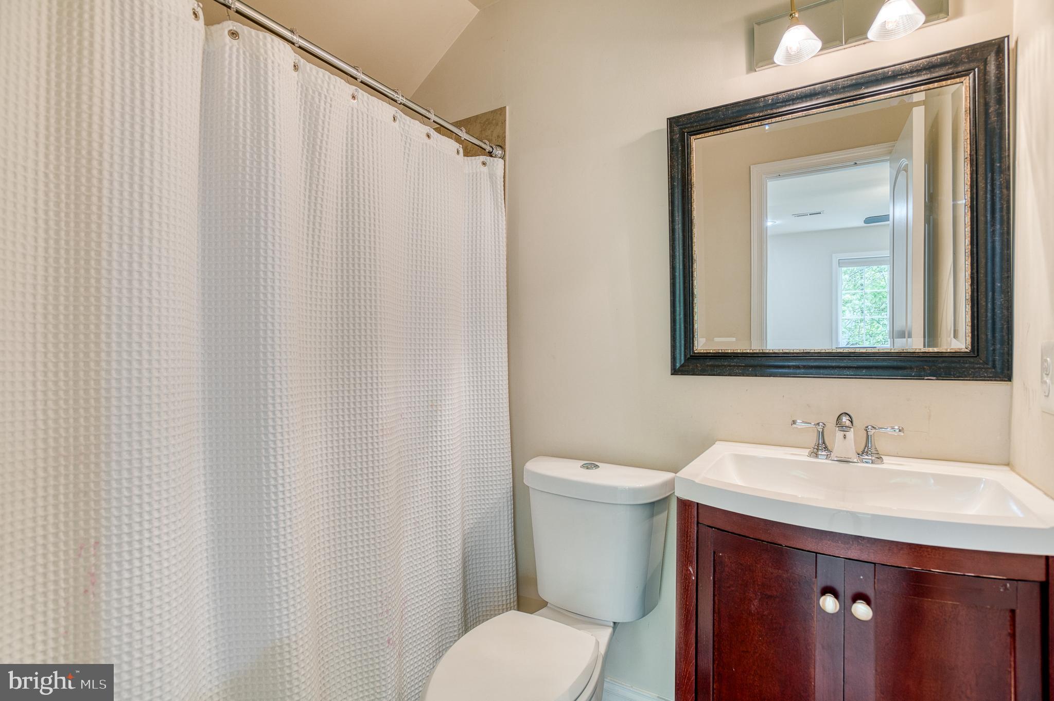 7140 Barry Road Alexandria, VA 22315 - Photo 41 of 56 a bathroom with a shower curtain sink and a mirror
