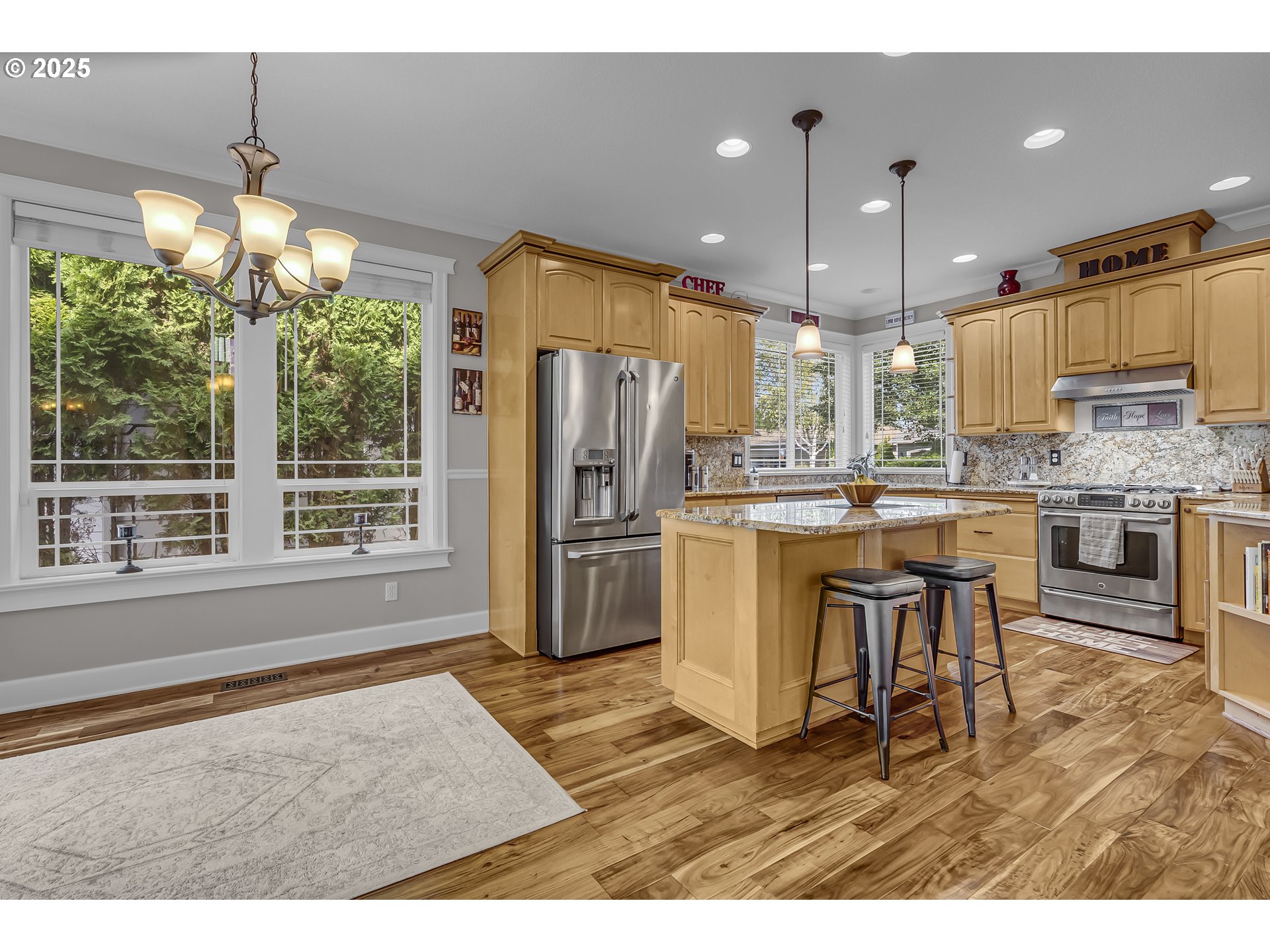 6336 Nicklaus Loop North Keizer, OR 97303 - Photo 12 of 45 a kitchen with stainless steel appliances kitchen island granite countertop a refrigerator a stove a oven and a dining table with wooden floor