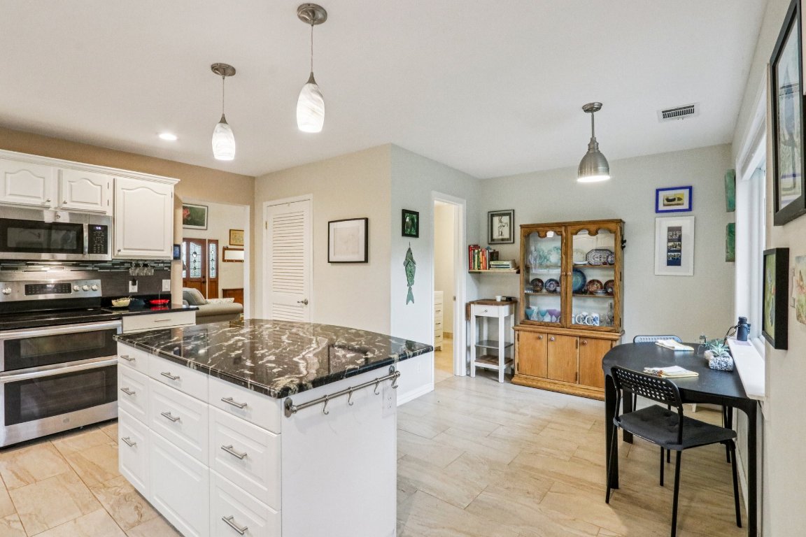 428 Gotier Trace Road Smithville, TX 78957 - Photo 13 of 40 Kitchen with appliances with stainless steel finishes, hanging light fixtures, white cabinetry, a center island, and dark stone counters