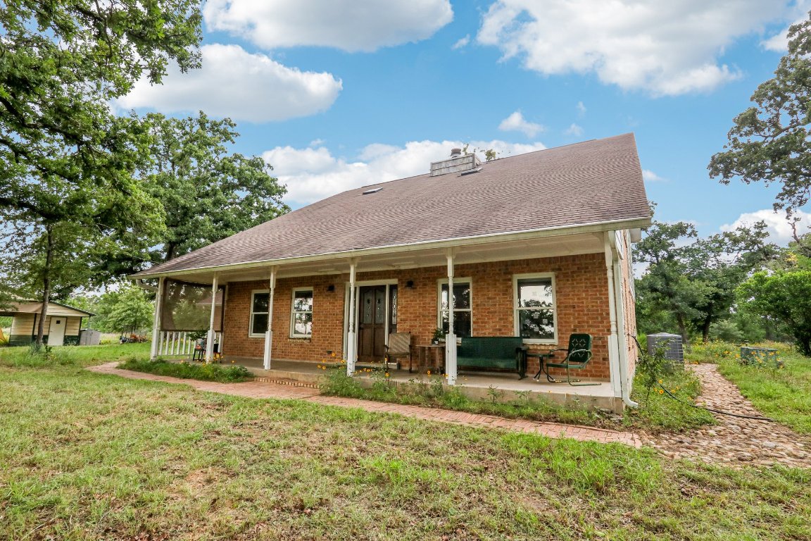 428 Gotier Trace Road Smithville, TX 78957 - Photo 5 of 40 Rear view of house with covered porch, brick siding, a lawn, a chimney, and roof with shingles