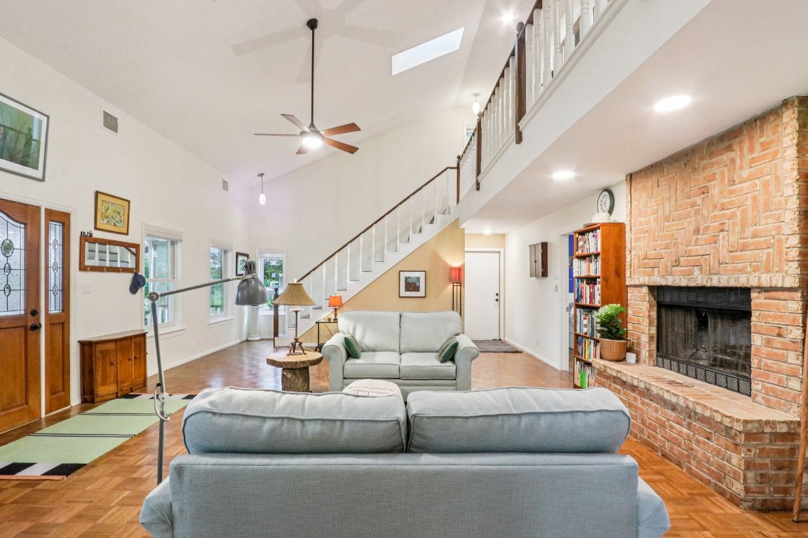 428 Gotier Trace Road Smithville, TX 78957 - Photo 8 of 40 Living area with a fireplace, stairway, a high ceiling, and a ceiling fan