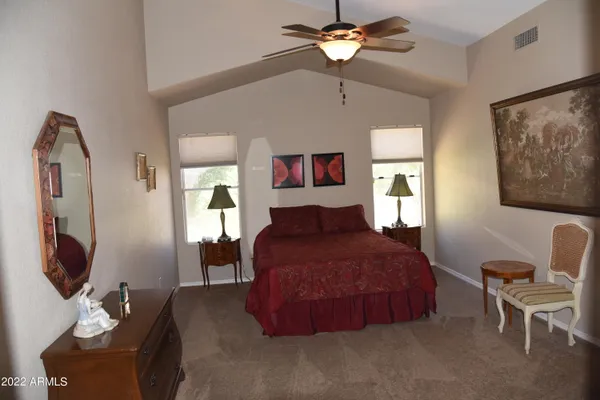 a spacious bedroom with a bed mirror furniture and a flat screen tv