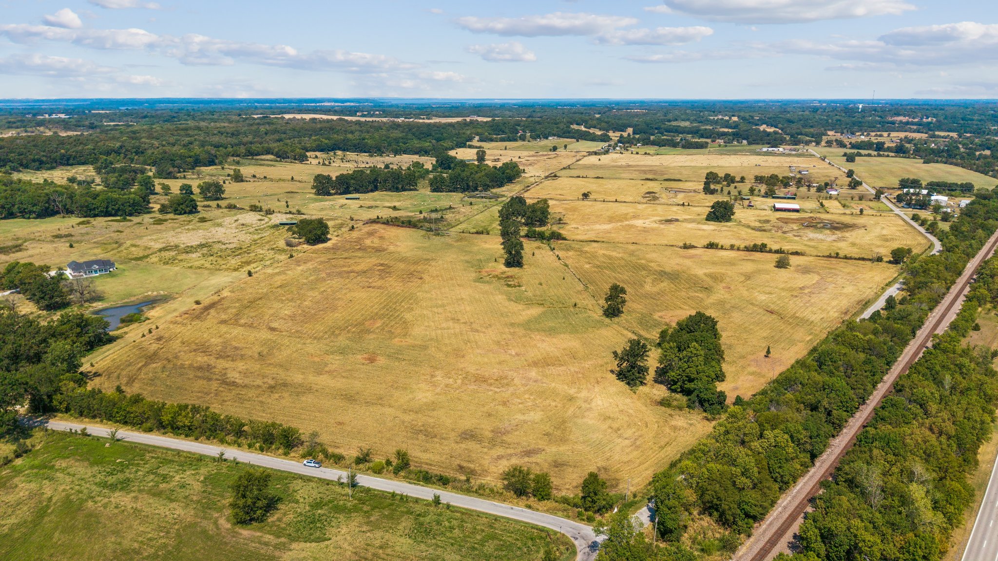 0 4190th Road Claremore, OK 74017 - Photo 3 of 5 Expansive agricultural land featuring fields, scattered trees, and a distant body of water