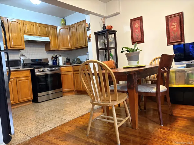 a kitchen with stainless steel appliances granite countertop a stove top oven a sink dishwasher and a dining table with wooden floor