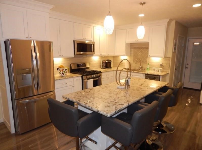 8821 Woodruff Street Houston, TX 77012 - Photo 5 of 20 a kitchen with stainless steel appliances granite countertop a refrigerator a stove a sink dishwasher a dining table and chairs with wooden floor