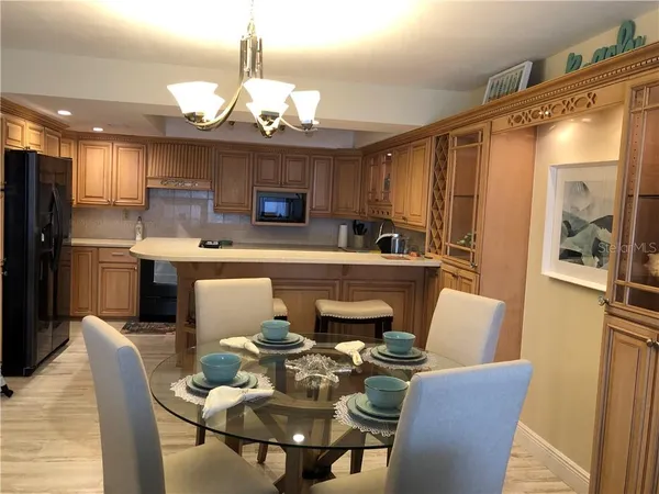 a kitchen with stainless steel appliances kitchen island granite countertop a dining table chairs and a refrigerator
