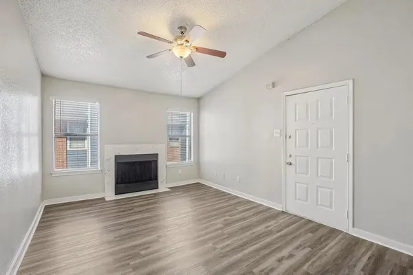 an empty room with wooden floor fireplace and windows