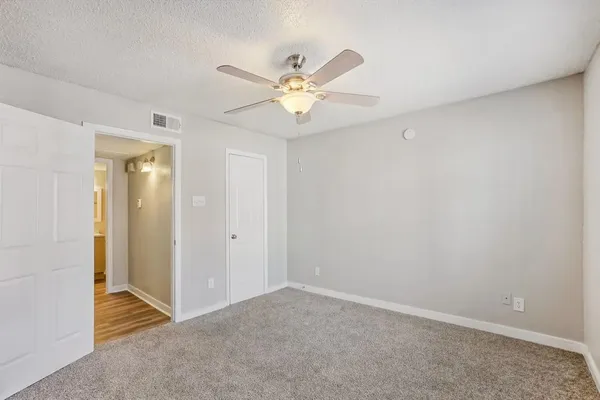an empty room with closet and a chandelier fan